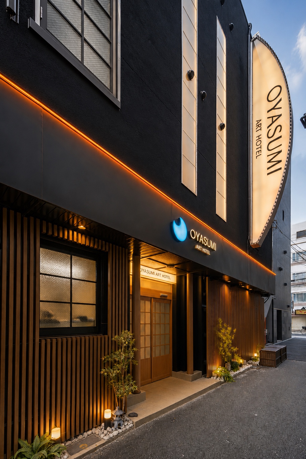 夕暮れに灯りがともる OYASUMI ART HOTEL の建物外観